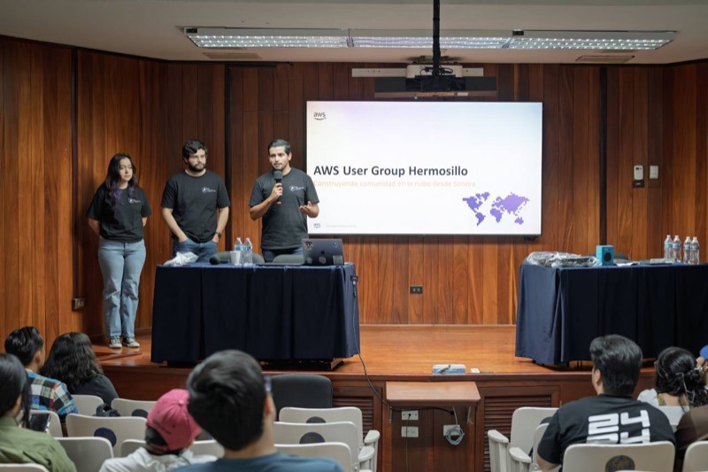 Panel de tres miembros del AWS User Group Hermosillo presentándose ante una sala llena en un auditorio