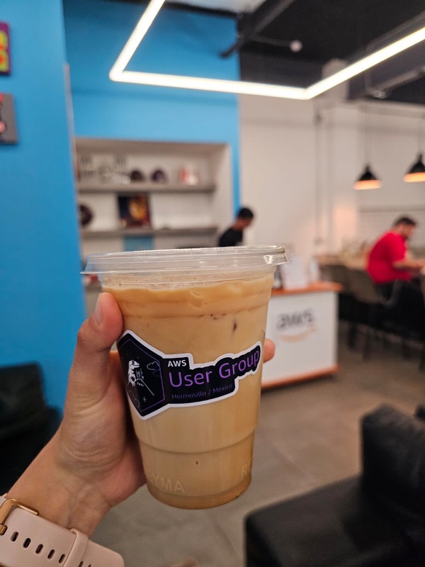 Café helado con una calcomanía del AWS User Group Hermosillo, en la cafetería sede de un encuentro