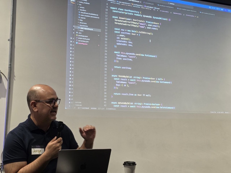 Jorge Rodríguez presentando LAMBDAGEDDON, con el código de un repositorio de DynamoDB proyectado en pantalla