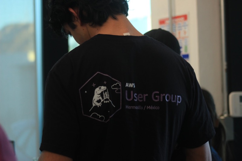 Reverso de una playera del AWS User Group Hermosillo, con el logo del gecko sobre las montañas